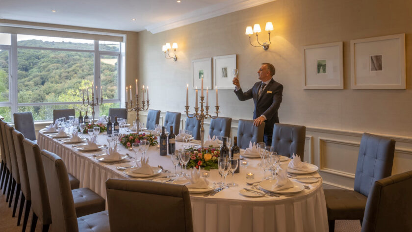 Elegant dining room with mountain view, featuring a long table set for a formal dinner, complete with candles and flowers.