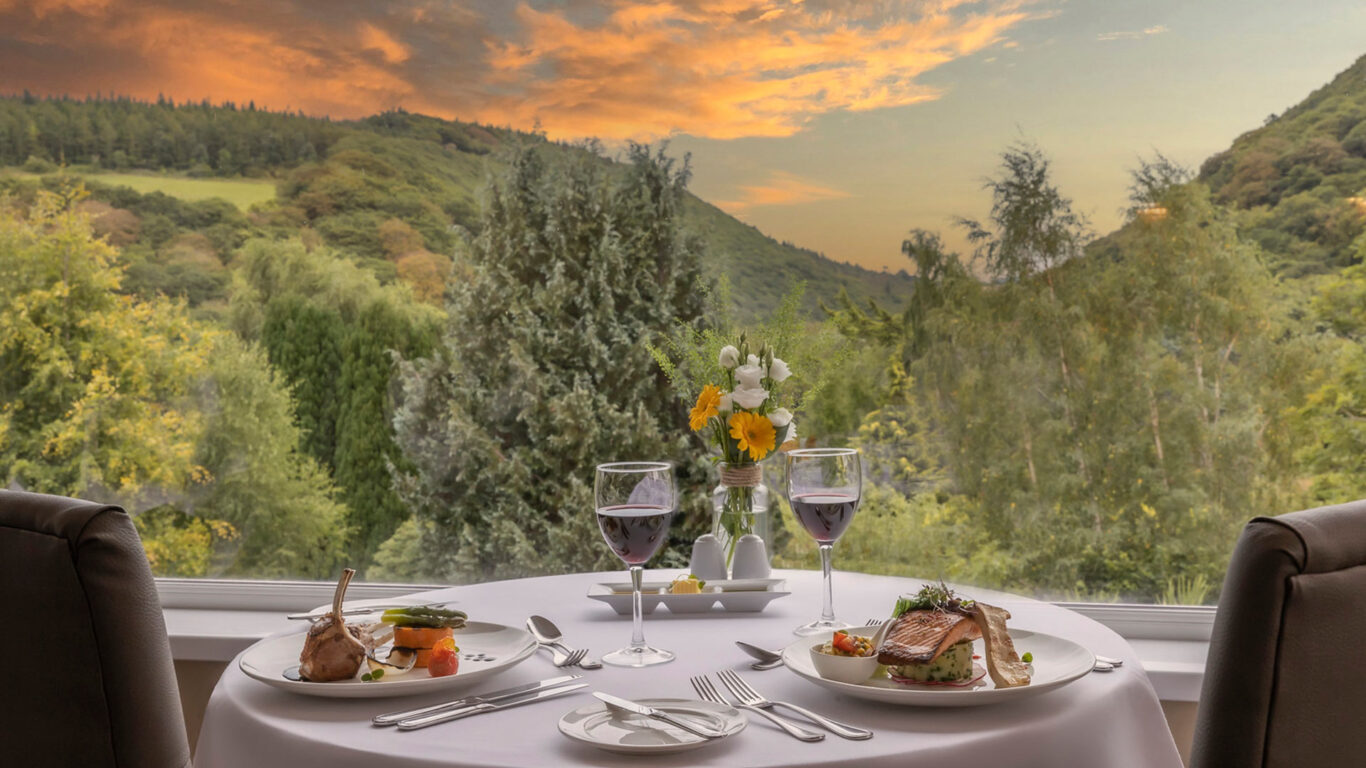 Savour fine dining with stunning sunset views over lush green hills, featuring elegant table settings and gourmet dishes.