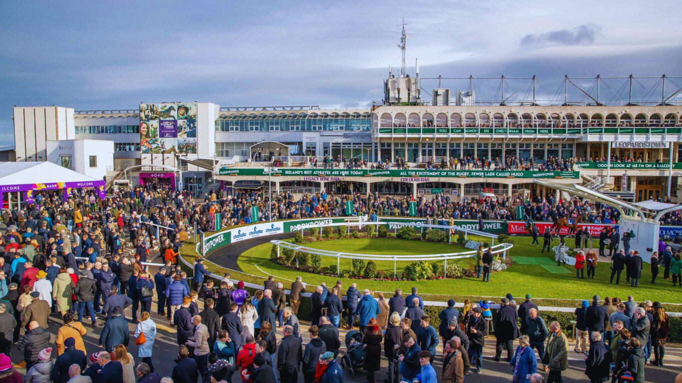 Guests enjoy a lively day at a vibrant racecourse, with a packed crowd and scenic grandstand, perfect for horse racing enthusiasts.