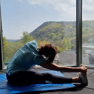 Guest enjoys yoga in a bright, modern room with panoramic mountain views, embodying relaxation and wellness at the hotel.