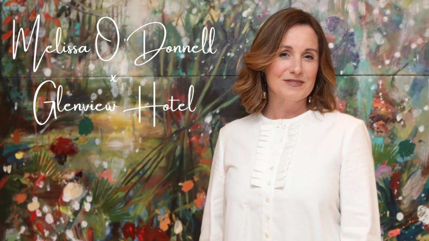 A woman in a white blouse stands in front of a colorful, abstract floral background with the text 