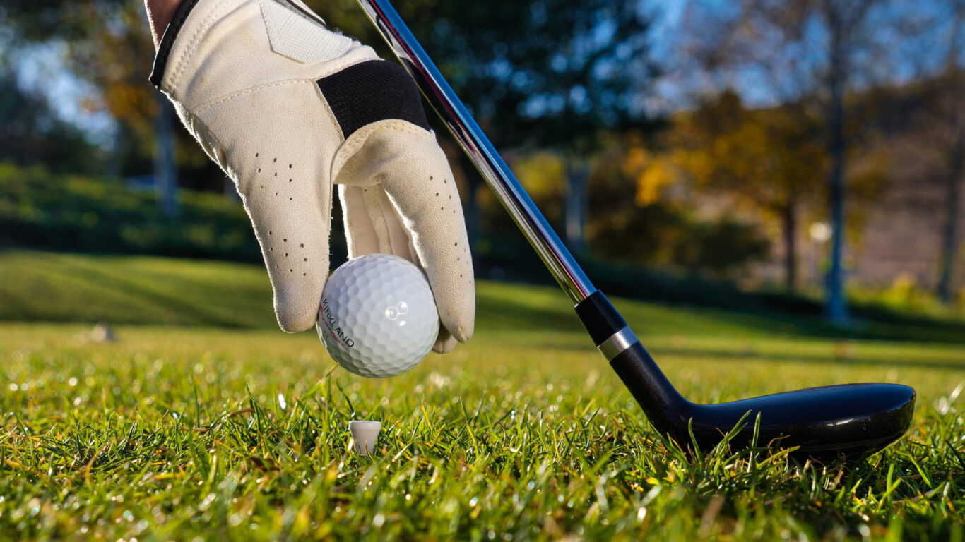 A golfer prepares to tee off at our scenic, lush golf course, perfect for relaxation and sport during your hotel stay.